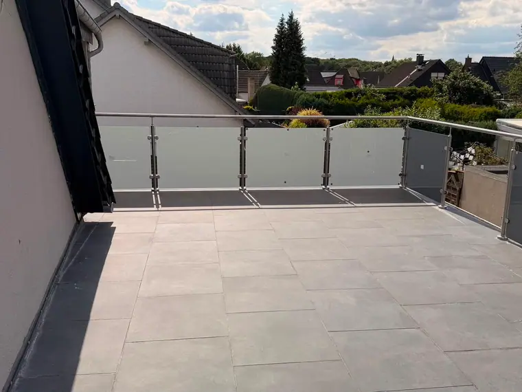 Glasgeländer mit Edelstahlpfosten auf einer gefliesten Dachterrasse
