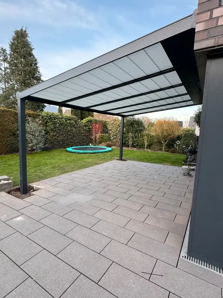 Freistehende Terrassenüberdachung auf gepflasterter Fläche im Garten