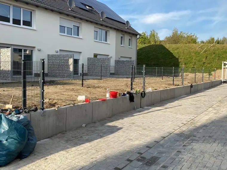 Doppelstabmattenzaun auf einer Betonmauer entlang eines Grundstücks