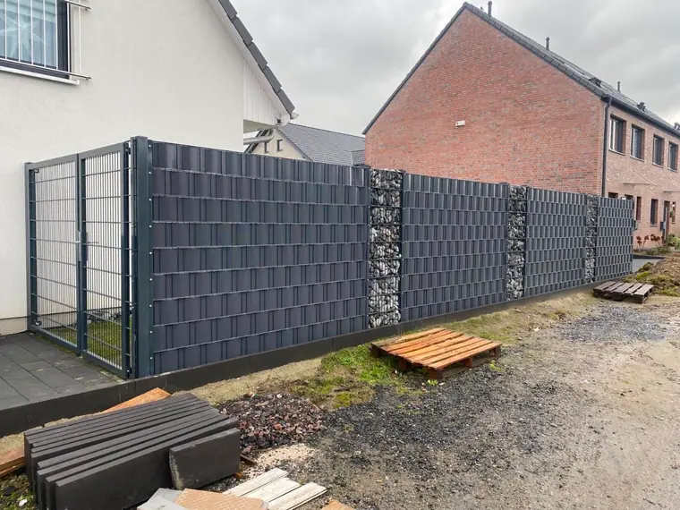 Doppelstabmattenzaun mit anthrazitfarbenen Sichtschutzstreifen, Gabionen-Feldern und Gartentor an einem Neubau
