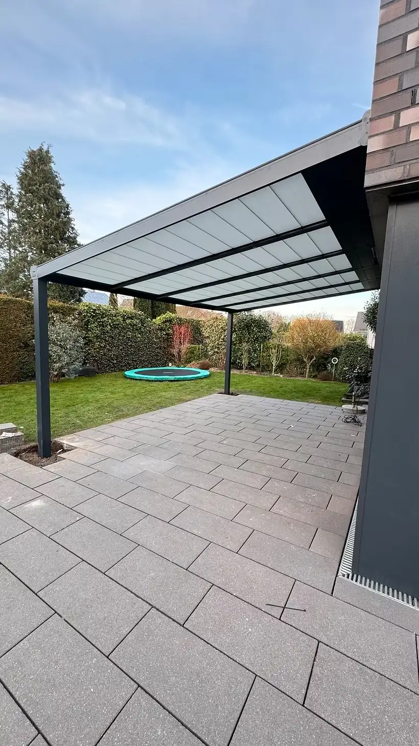 Fertig montierte Terrassenüberdachung aus Aluminium in der Dämmerung, warm beleuchtet