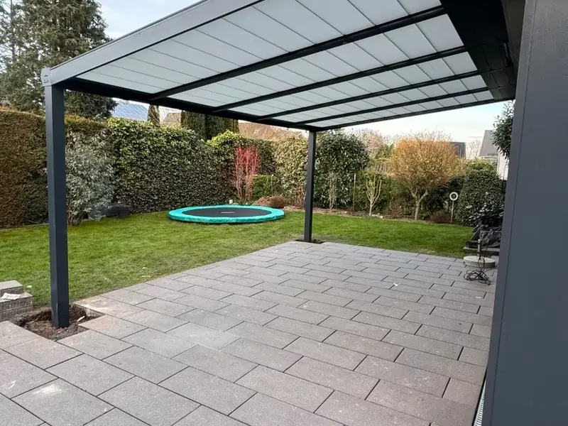 Fertig montierte Terrassenüberdachung aus Aluminium auf einer gepflasterten Terrasse